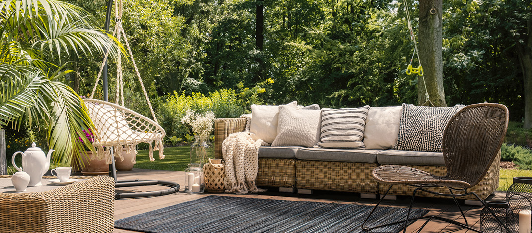 Ansprechende Outdoor-Gestaltung mit stilvollen Gartenmöbeln und Deko-Kissen, die den Trend Outdoor-Living veranschaulicht.