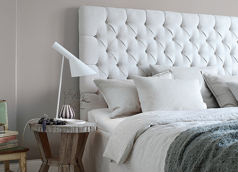 helles Bett mit grauer Wand im Hintergrund