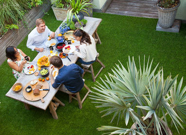 Einladende Outdoor-Gestaltung mit Kunstrasen, wo eine Gruppe von Freunden ein geselliges Essen genießt.