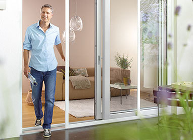 Outdoor-Living: Ein Mann tritt aus einer Terrassentür mit Insektenschutz.