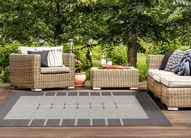 Eine Terrasse mit einem gemütlichen Outdoor-Teppich und stilvollen Gartenmöbeln.