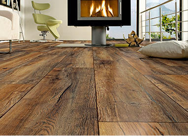 Boden-Trends: Nahaufnahme von einem dunkelen Holzboden. Im Hintergrund ist ein Kamin und ein Sofa zu sehen.